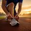 Pinesh Arimont, fitness enthusiast, tying running shoes on a track at sunrise